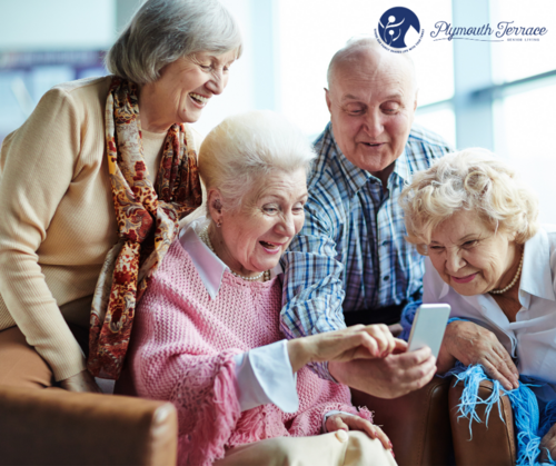 Elderly friends laughing and finding something funny on a phone.